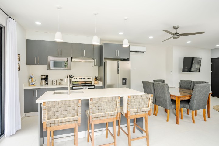 Modern kitchen and dining area with gray cabinets, island, and wooden furniture.