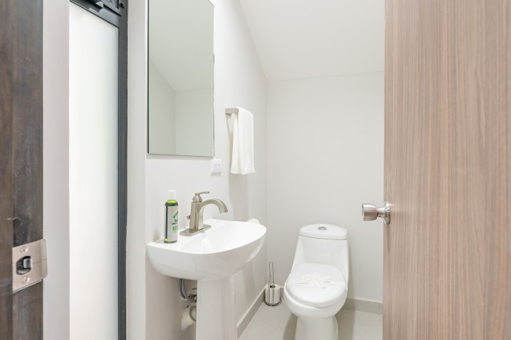Small bathroom with toilet, sink, mirror, and towel on wall.