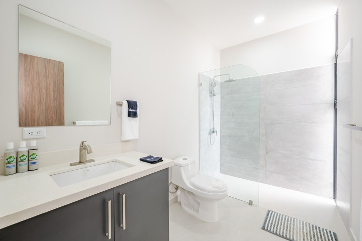 Modern bathroom with sink, mirror, toilet, and glass shower enclosure.