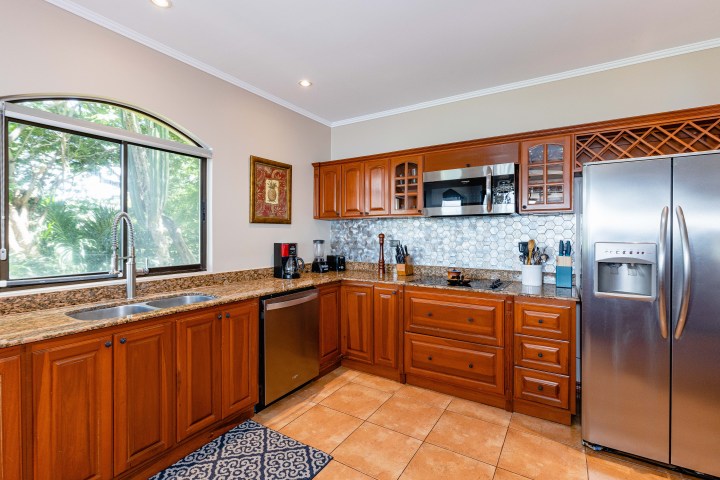 Modern kitchen with wooden cabinets, stainless steel appliances, and a large window.