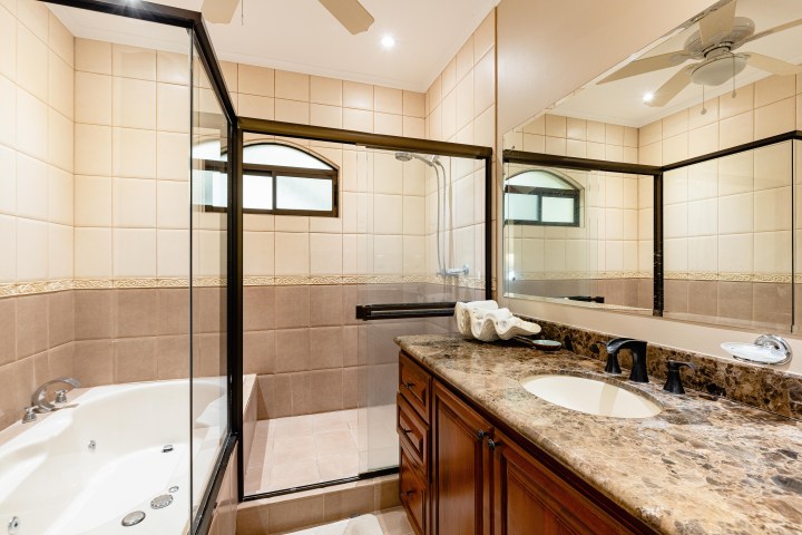 Modern bathroom with a marble countertop, glass shower, and bathtub.