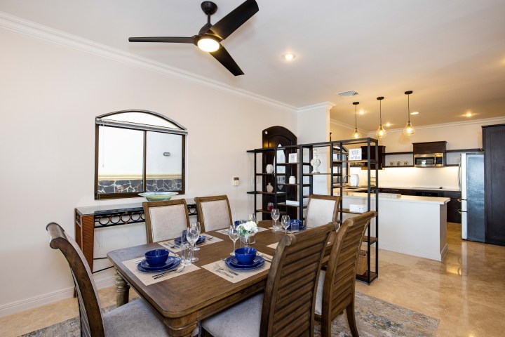 Modern dining room and kitchen with wooden furniture and pendant lights.