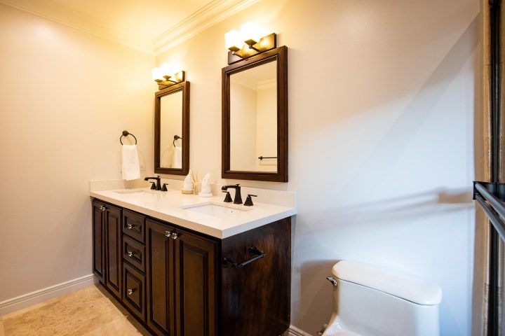 Bathroom with dual-sink vanity, two mirrors, and toilet.