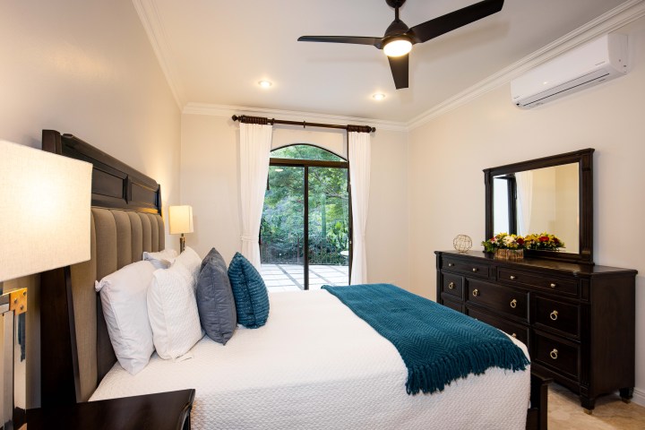 Cozy bedroom with bed, dresser, ceiling fan, and sliding glass door to garden.