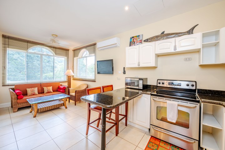 Bright kitchen and living area with wooden furniture and tiled flooring.