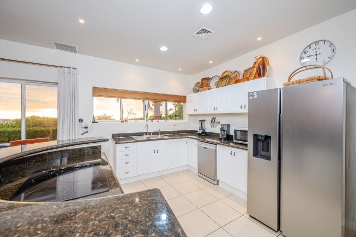 Modern kitchen with white cabinets, stainless steel appliances, and large windows.