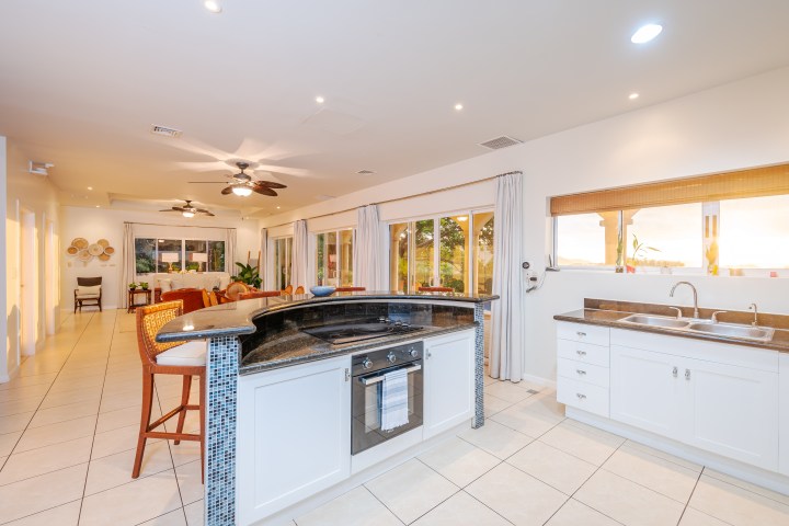 Bright kitchen with island, stools, and large windows overlooking a sunset view.