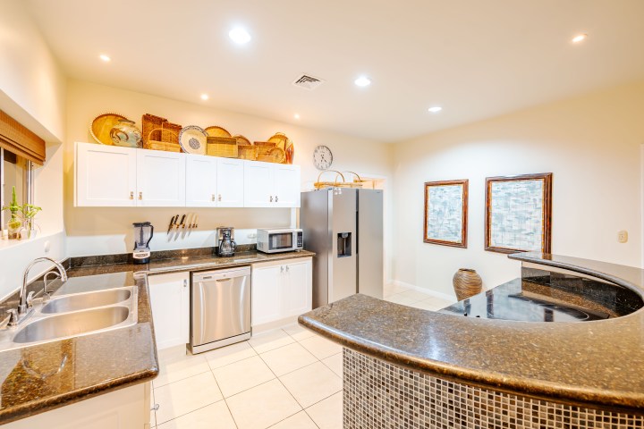 Modern kitchen with white cabinets, stainless appliances, and decorative items on top cabinets.