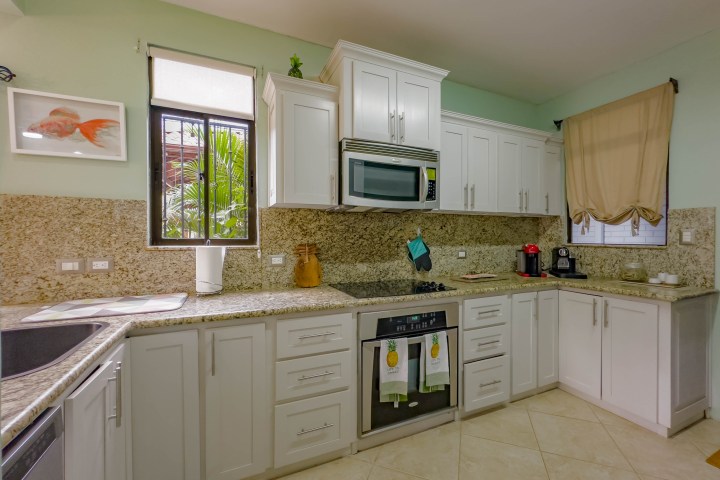 Modern kitchen with white cabinets, granite countertops, and appliances like oven and microwave.