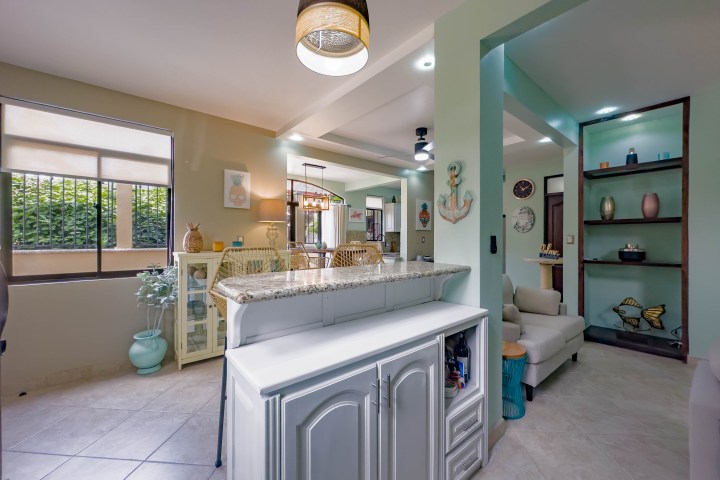 Coastal-themed living area with light green walls, wicker chairs, and decorative anchor.