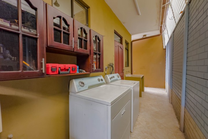 Laundry room with washer and dryer, cabinets, and toolbox on a countertop.