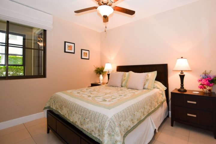 Cozy bedroom with bed, two bedside tables, lamps, and a ceiling fan.
