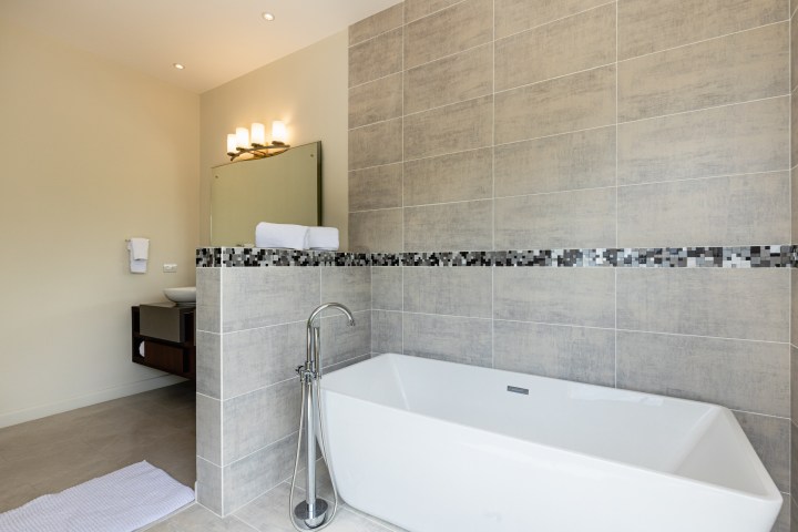 Modern bathroom with freestanding tub, tiled walls, and vanity with mirror.