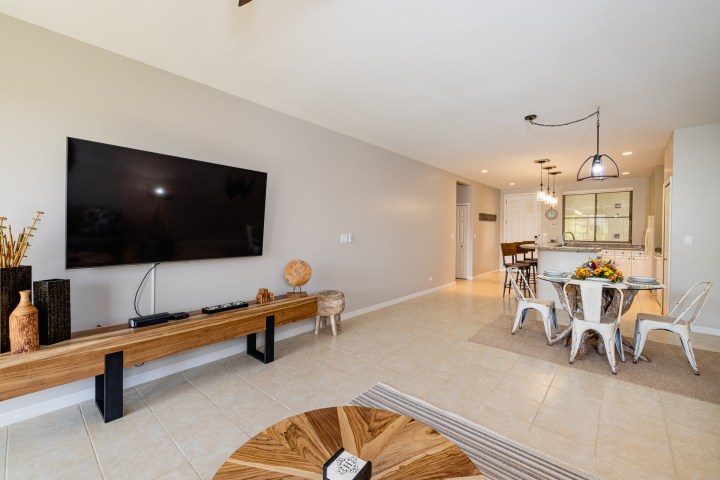 Modern living room and kitchen with TV, dining table, and wood accents.
