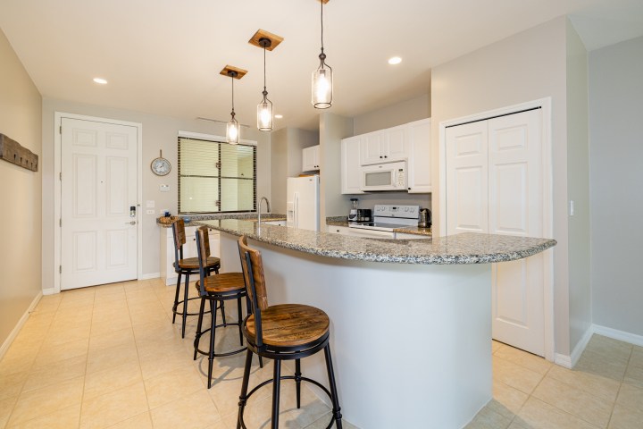 Modern kitchen with a curved granite countertop, bar stools, and pendant lights.