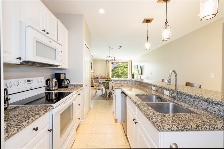 Modern kitchen with granite countertops, white cabinets, and stainless steel appliances.