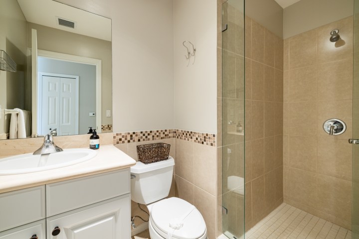 Modern bathroom with a sink, toilet, and beige tiled shower.
