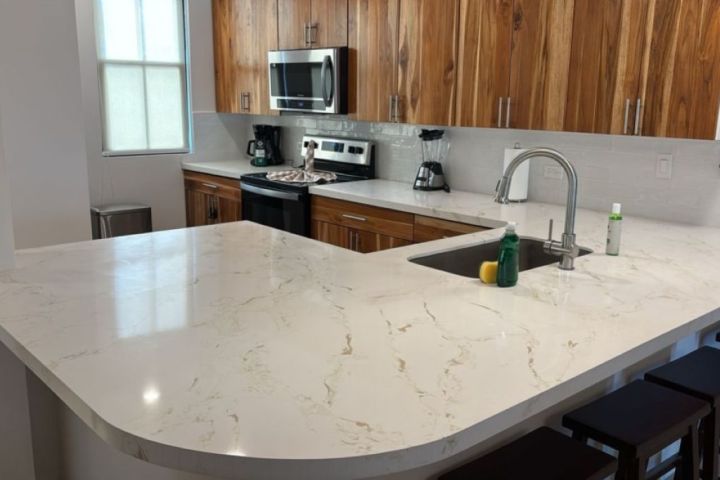 Modern kitchen with marble countertop, wooden cabinets, and stainless steel appliances.