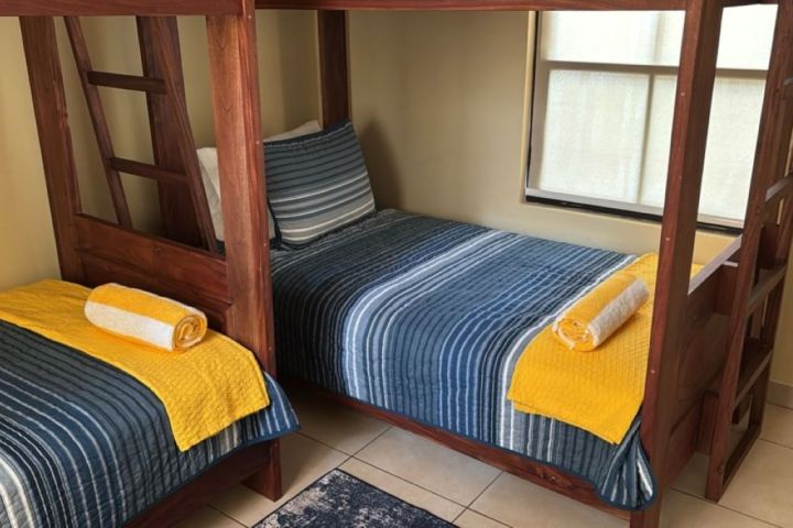 Two bunk beds with blue striped bedding and rolled yellow towels in a bright room.