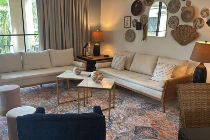 Cozy living room with beige sofas, decorative wall plates, and a patterned rug.