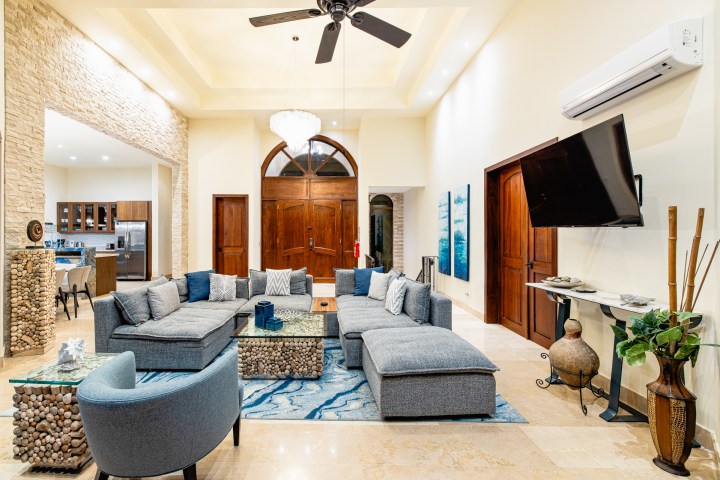 Spacious living room with gray sectional sofa, blue accents, and wall-mounted TV.