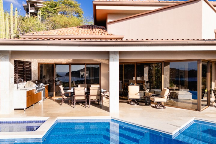Modern house with a poolside patio, outdoor kitchen, and glass sliding doors.