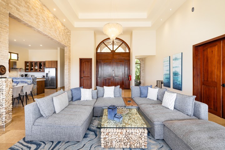Spacious living room with gray sectional, stone accent wall, and chandelier.