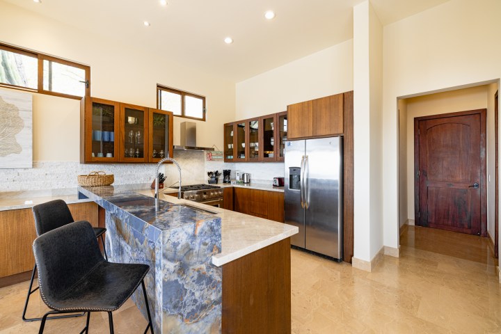 Modern kitchen with wood cabinets, marble countertops, and stainless steel appliances.