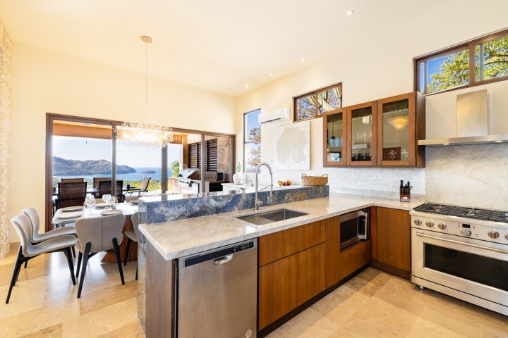 Modern kitchen and dining area with ocean view and large windows.