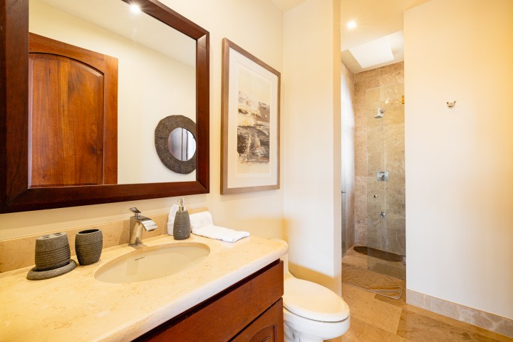Modern bathroom with wooden mirror, sink, toilet, and glass shower.