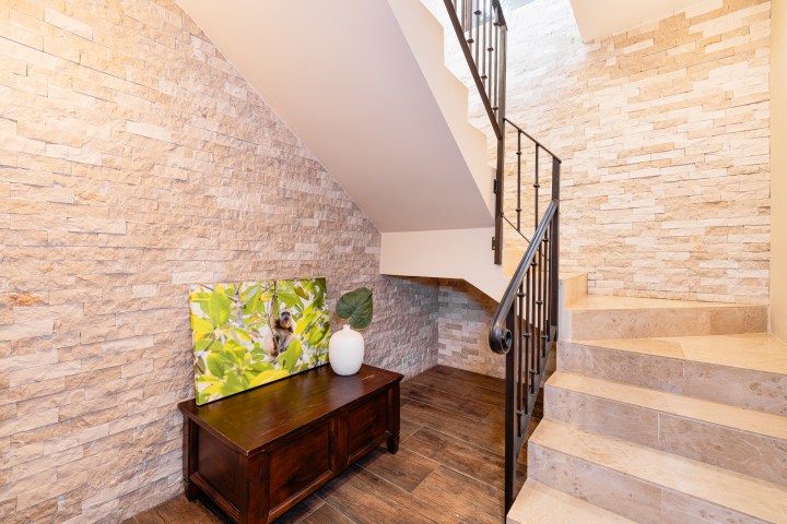 Interior staircase with stone walls, wooden bench, and a potted plant.