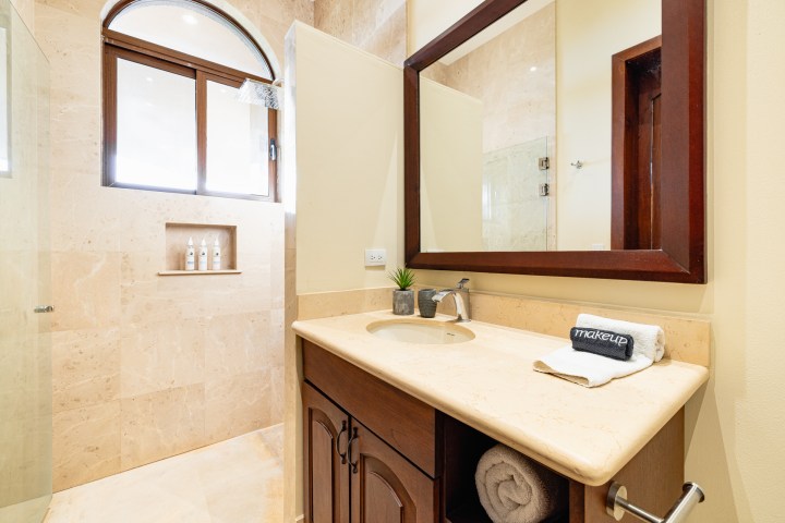 Modern bathroom with large mirror, beige countertop, and shower area with glass partition.
