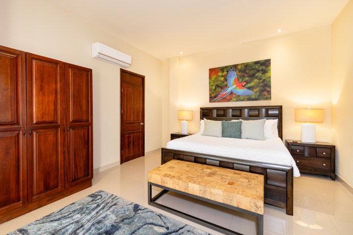 Bedroom with wooden furniture, a large bed, bird artwork, and two lamps on side tables.