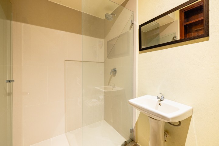 Minimalist bathroom with glass shower, wall-mounted sink, and rectangular mirror.