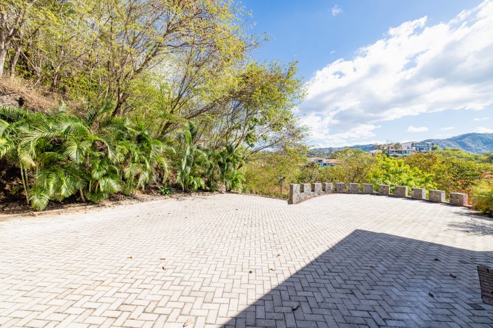 Paved patio with surrounding trees, distant houses, and a mountainous backdrop.