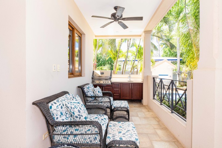 Outdoor patio with wicker chairs, cushions, a ceiling fan, and a barbecue grill.