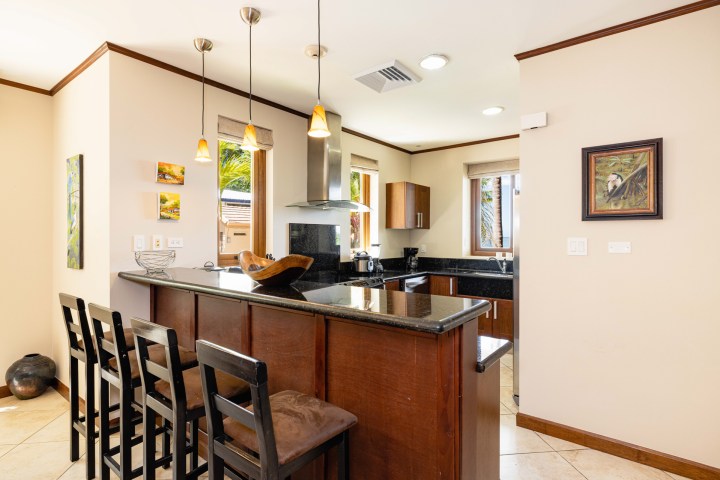 Modern kitchen with bar seating, hanging lights, and artwork on the walls.