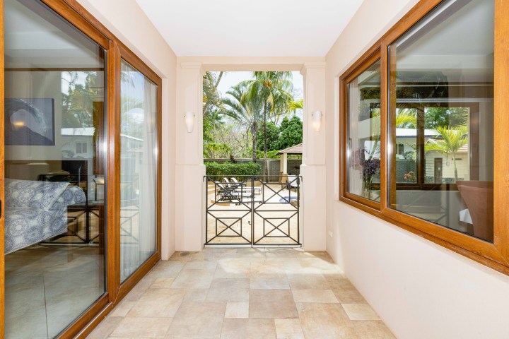 Interior corridor with sliding glass doors and view of patio with palm trees.