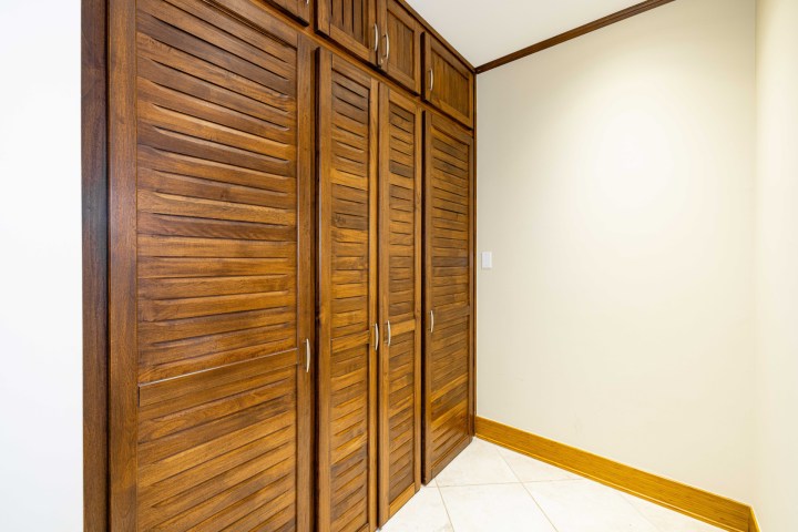 Wooden louvered closet doors in a neutral-colored room corner.