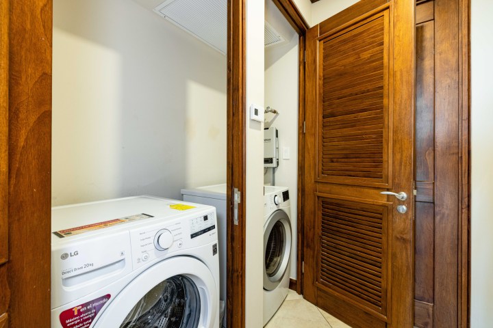 Laundry closet with washing and drying machines behind wooden doors.