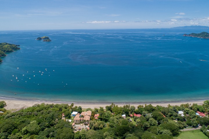 Aerial view of a coastal landscape with lush greenery and boats on the water.