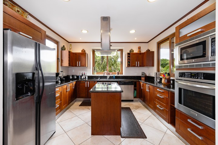 Modern kitchen with stainless steel appliances, wooden cabinets, and a central island.