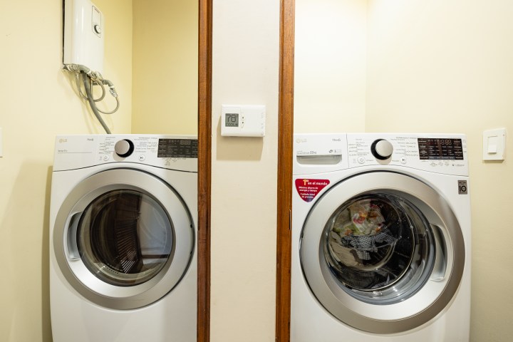 Two white front-loading washing machines side by side in a light-colored room.
