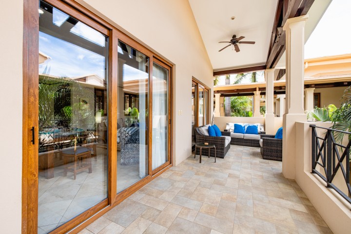 Modern patio with wicker furniture, blue cushions, sliding glass doors, and ceiling fan.