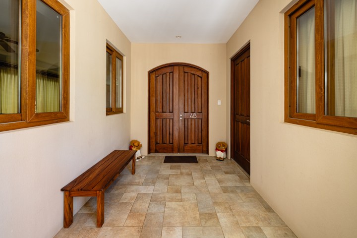 Hallway with wooden bench, door labeled 4B, and decorative statues on tile floor.