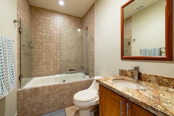 Modern bathroom with a tub, tiled walls, wooden vanity, and mirror above sink.