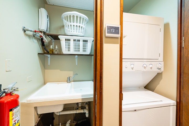 Laundry room with washer, dryer, sink, shelves, and fire extinguisher.