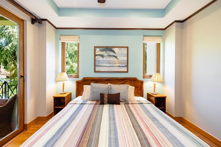 Bedroom with large bed, striped bedding, two lamps, and wall art.