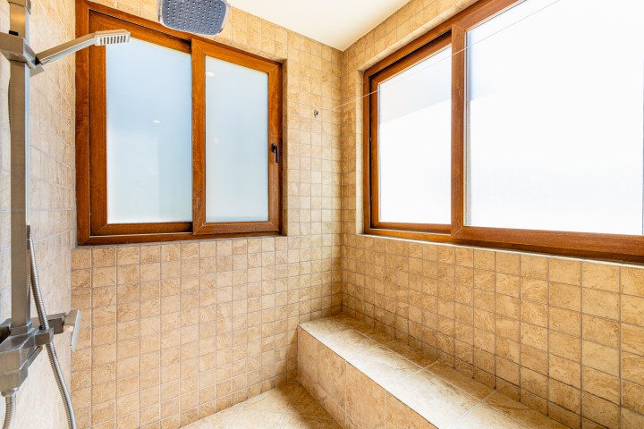 Tiled shower with wooden-framed windows and a large showerhead.