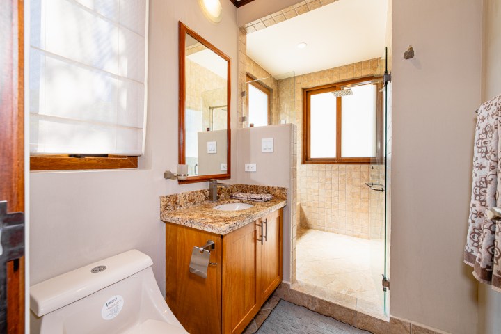 Modern bathroom with a glass shower, wooden vanity, and granite countertop.